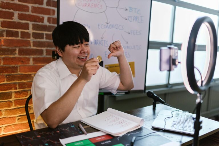 Asian male vlogger discussing cryptocurrency trading in an online video setup.