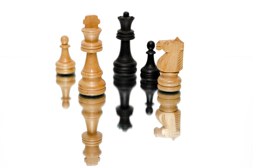 Strategic chess pieces reflecting on a glossy surface, emphasizing strategy and challenge.